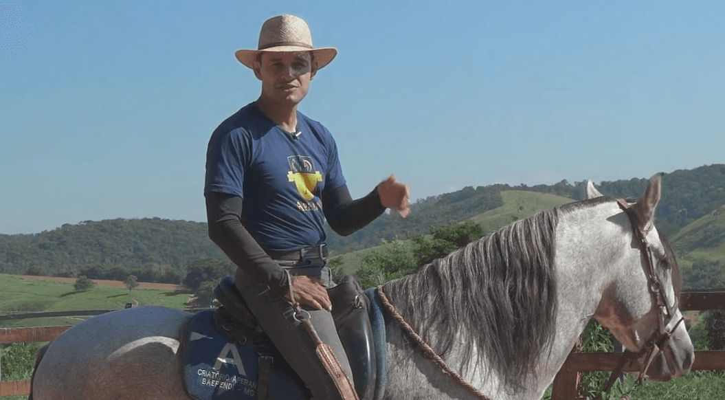 Foto do Fabiano com um chapéu, montando em um cavalo branco